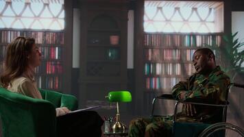 Wounded armed forces veteran in wheelchair discussing about war scenes, tells stories about horror of the combat. Distressed soldier with disability trying to recover with psychologist. Camera A. video