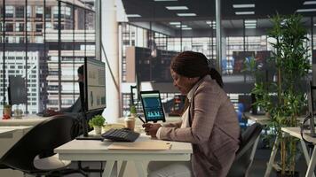 Black business employee browses social media webpages on her phone, taking a short break to answer a few texts at the office. Female worker does online communication via texting. Camera B. video