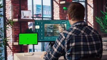 Man in home office uses AI program turning text prompt into videos next to isolated screen tablet. Person using text to generative models on computer and chroma key device, camera A