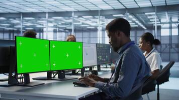 Technician using multi monitor green screen computer setup, working in server farm to optimize it for data processing requirements. Man doing developing on chroma key PC in data center video