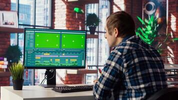 editor wearing headphones to polish footage and improve audio quality on green screen PC. Videographer professionally adjusting clips, applying sound effects using chroma key computer, camera B video
