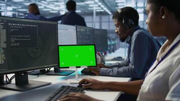 Close up of green tablet in server room used by system administrators to ensure minimal downtime. Data center software developers looking at chroma key device, monitoring performance, camera A video