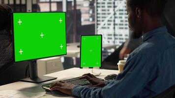 Black businessman analyzing financial data next to chroma key screen, reviewing company strategies on pc and contributing to business development and decision making. Successful forecast. Camera A. video