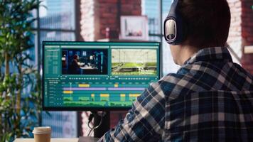 editor wearing headphones doing montage, using specialized software application, zoom in shot. Freelancer using editing tools on PC to cut movie project footage, camera A closeup video