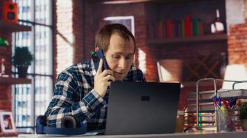 Manager in home office sitting at desk in front of laptop, calling employee to confront him about mistakes. Supervisor using notebook to do job online, doing telephone call to scold worker, camera B video