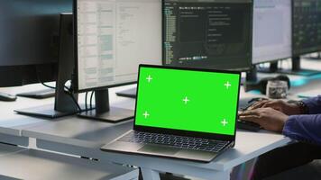 Employees using green screen laptop, working in server farm to optimize it for data processing requirements. Close up of mockup notebook on desk next to workers coding in data center, camera A video