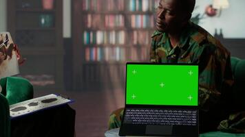 Military trooper studies Rorschach inkblot illustration next to green screen in therapy with psychologist, addressing PTSD and trauma recovery problems. Psychological support. Camera B. video