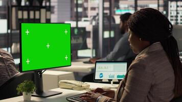 Businesswoman at office desk looks at green screen on device, studying documents and infographics to support effective decision making and company objectives. Administrative tasks. Camera A. video