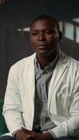 Vertical Doctor in white coat opening up about his medical career struggles, suffering from anxiety and mental health issues. Therapist listens with empathy, discussing grief and emotional support. Camera A. video