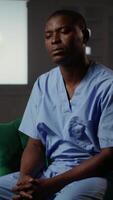 Vertical Black medical assistant being defocused and disconnected from reality, suffering from depersonalization and PTSD and receiving help from therapist. Male nurse opens up about struggles. Camera B. video
