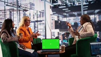 Multiethnic women discussing new strategies next to green screen, reviewing performance metrics and other data for evaluation. Group of leaders working in a men dominated environment. Camera B. video
