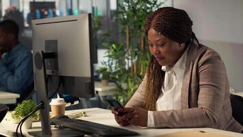 afrikansk amerikan chef tar en ha sönder från företag arbete och bläddring social media, checkar meddelanden och webbplatser på henne skrivbord. analytiker göra flera saker samtidigt och textning under schema. kamera a. video