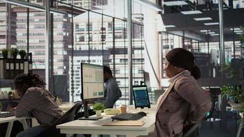 Woman CEO suffers from muscle cramps due to incorrect posture at the desk, dealing with neck and back ache while he solves tasks at workstation. Director with spasm and sedentary life. Camera B. video