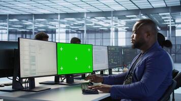 Engineer using green screen computer, working in server farm to optimize it for data processing requirements. IT professional coding on mockup PC in data center, camera A video