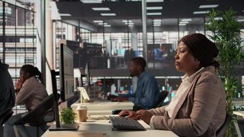 focado africano americano geral Gerente multitarefa às escrivaninha para resolver o negócio tarefas e operações em computador e documentos. mulher encontro prazos enquanto fazer estratégico decisões. Câmera b. video