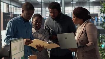 Staff members and leader analyzing financial data in order to create a new balance report, dealing with the annual paperwork to ensure a useful resource allocation for business success. Camera A. video