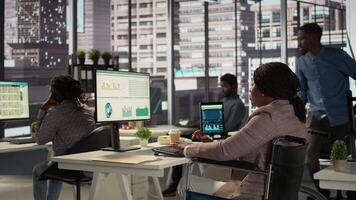 Black manager wheelchair user reviewing the financial data for the monthly reports, ensuring an accurate revenue balance. Woman with disability solving business operations. Camera B. video