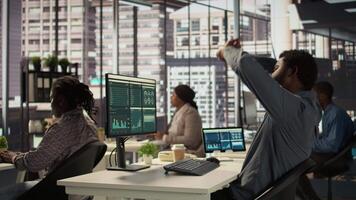Black male CEO dealing with back pain and stretching his muscles at the desk, sitting with an incorrect posture and trying to fix it. General manager working with data analytics. Camera B. video