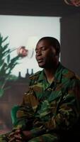 Vertical Black military officer in army uniform attends counseling session, looking distressed and opening up about post traumatic combat stress. War soldier dealing with shell shock. Camera B. video