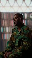 Vertical African american soldier looks distressed during a counseling session for trauma recovery, trying to open up and share his grief. PTSD support and mental health treatment for combatant. Camera B. video