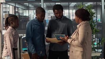 Black leader reviews company strategy with her team members in a modern corporate office, making key business decisions to support organizational growth. Discuss resource allocation. Camera A. video