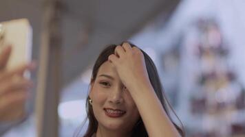 Elegant woman in a purple blazer using her smartphone, gracefully waving in a modern outdoor setting. A blend of style, technology, and sophistication with a warm and cheerful expression. video