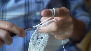 Close up of elderly hands skillfully crocheting a blue piece, capturing the delicate details of needlework and the dedication to the art of creating handmade crafts. video