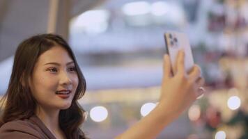 Elegant woman in a purple blazer using her smartphone, gracefully waving in a modern outdoor setting. A blend of style, technology, and sophistication with a warm and cheerful expression. video