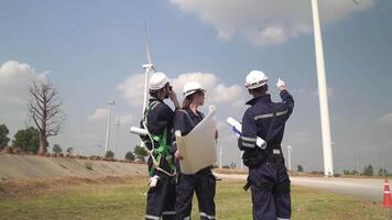 Engineers man and woman inspecting construction of WIND TURBINE FARM. WIND TURBINE with an energy storage system operated by Super Energy Corporation. Workers Meeting to check AROUND THE AREA. video