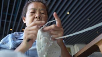Close up of elderly hands skillfully crocheting a blue piece, capturing the delicate details of needlework and the dedication to the art of creating handmade crafts. video