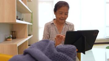 Elderly woman knitting in a cozy room, focused on creating a beautiful piece with blue yarn. A serene moment showcasing craftsmanship, creativity, and the joy of handmade art. video