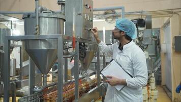 The production control supervisor inspects and controls the operation of machines in the manufacturing line of a canned fish industry video