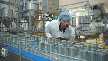 Production control supervisor inspects and controls the operation of each step in the production line of a canned fish factory video