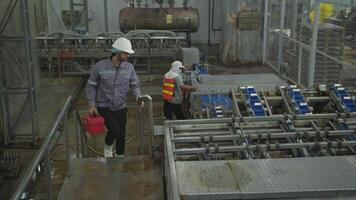 Factory technicians perform routine machinery inspections while the production process is running on the production line video