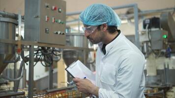 The production control supervisor inspects and controls the operation of machines in the manufacturing line of a canned fish industry video