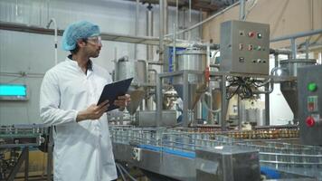 Production control supervisor inspects and controls the operation of each step in the production line of a canned fish factory video