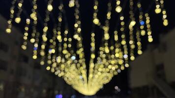 A breathtaking and stunning display of vibrant yellow lights cascades beautifully during the night, creating an enchanting and magical atmosphere in a lively, energetic urban environment video
