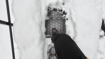 In a captivating winter scene, vivid and colorful boots rest on a metal grate, surrounded by an expanse of deep, pristine snow, which invites all adventurers to explore the chilly outdoors video