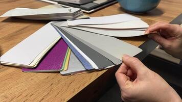 Currently examining various color samples and swatches on a wooden table for an upcoming design project video
