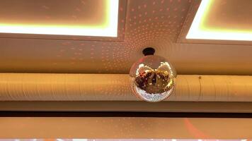 A dazzling disco ball hangs from the ceiling, casting vibrant light patterns that create an energetic atmosphere perfect for unforgettable parties and joyful celebrations video