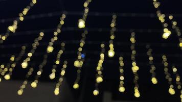 Twinkling yellow lights hang gracefully in delicate, shimmering strands, creating a warm and inviting ambiance that contrasts beautifully against the dark background that surrounds them video