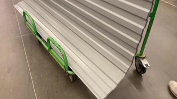 Flat metal sheets of various sizes and thicknesses are neatly organized on a durable green roller cart, designed for easy transport and optimal storage in construction or manufacturing video