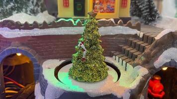 A beautiful miniature display featuring a sparkling Christmas tree set in a snowy landscape with charming village architecture, ideal for sophisticated holiday decor and celebrations video