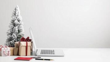 A minimalist Christmas office setup with a laptop, snow-covered mini tree, wrapped gifts with red ribbons, and candy canes on a white desk, adding a festive touch to a professional workspace photo