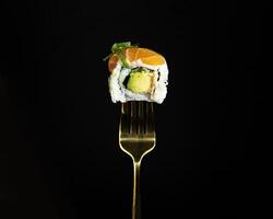 Japanese salmon sushi on a fork on the dark background photo