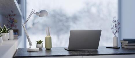 A back view of a laptop, a table lamp, and decor on a table in a modern home office workspace. photo