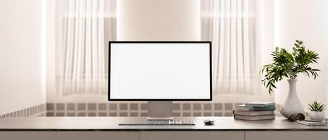 A computer with a white screen mockup and decor on a table in a minimalist and cozy room. photo
