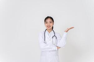 A female doctor smiling warmly and presenting with an open palm, as if recommending something. photo