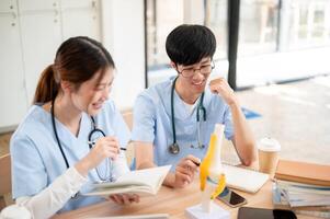 A female medical student is examining a model of bone joints and discussing it with her classmate. photo