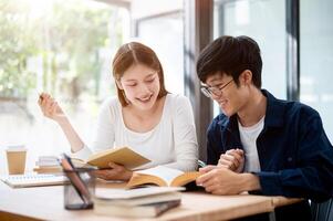 Two young Asian college students are studying and preparing for an exam together in a coffee shop. photo